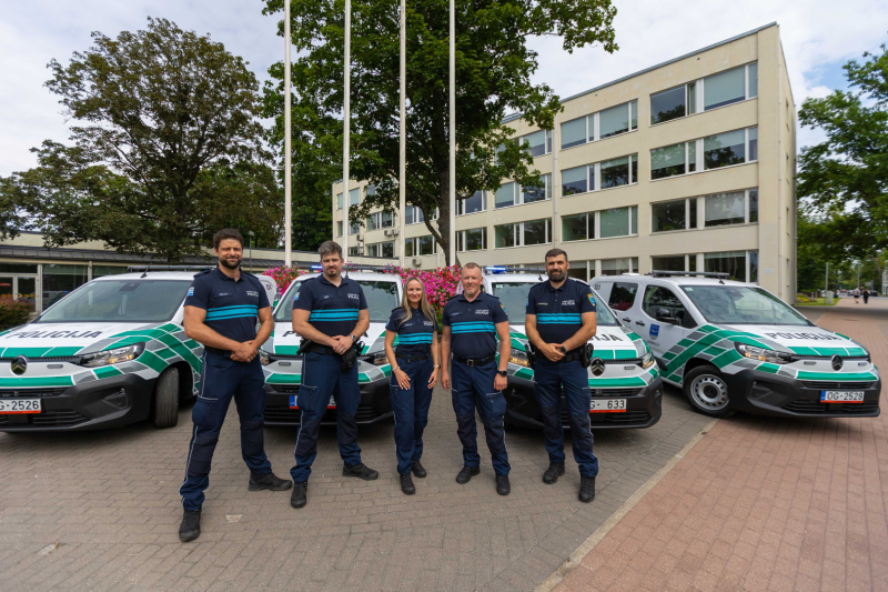 Policijas auto un priekšplānā policijas darbinieki