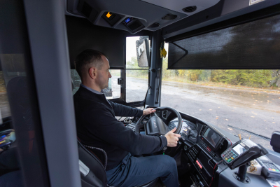 Autobusa vadītājs sēž pie stūres, vadot autobusu