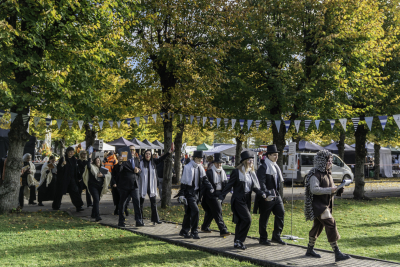 cilvēku grupa iet teatrālā gājienā