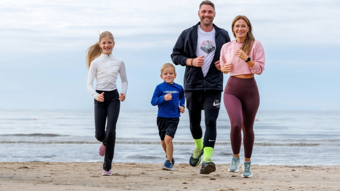 sportiska ģimene skrien gar jūru