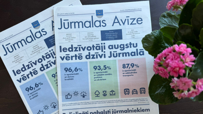 Uz galda stāv divas Jūrmalas avīzes aprīļa numurs, blakus ziedi