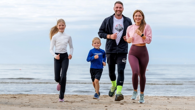 sportiska ģimene skrien gar jūru