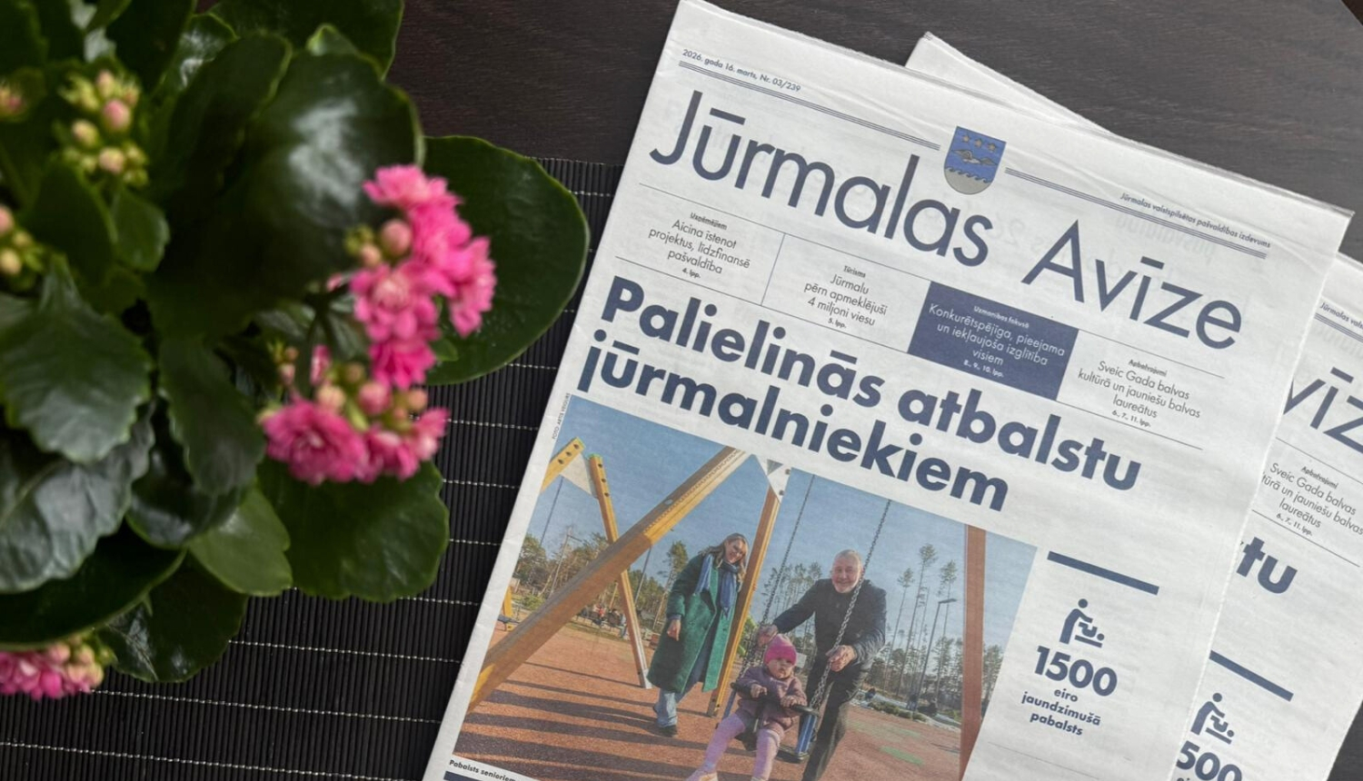 Jūrmalas avīzes marta numurs uz galda, blakus rozā puķes podiņā