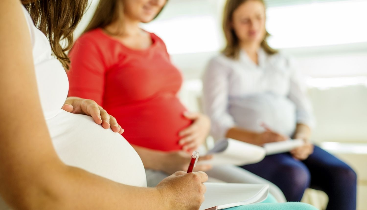 Grūtnieces piedalās izglītojošā nodarbībā, sēžot aplī un veicot pierakstus
