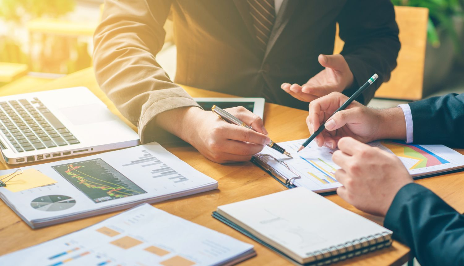 Divi biznesa cilvēki sēž pie galda un apspriež finanšu dokumentus un grafikus