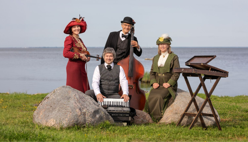 Četri mūziķi retro stilā stāv un sēž pie jūras, pozējot ar saviem instrumentiem