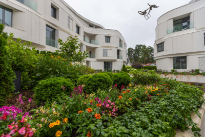 skaists sakopts īpašums ar puķu dobēm pie modernas daudzdzīvokļu mājas