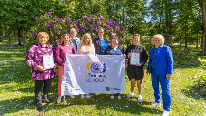 Pedagogi no Jūrmalas Pumpuru vidusskolas un pirmsskolas izglītības iestādes “Zvaniņš”  tur rokā “eTwinning Skola” karogu