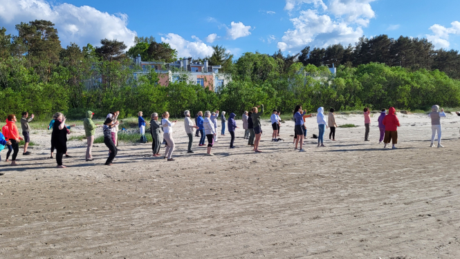 Cilvēki vingro pludmalē