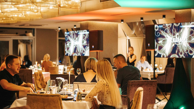 Restorāns, kurā cilvēki sēž pie galdiņiem