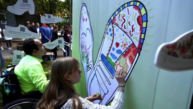 Meitene zīmē uz sienas plakātu