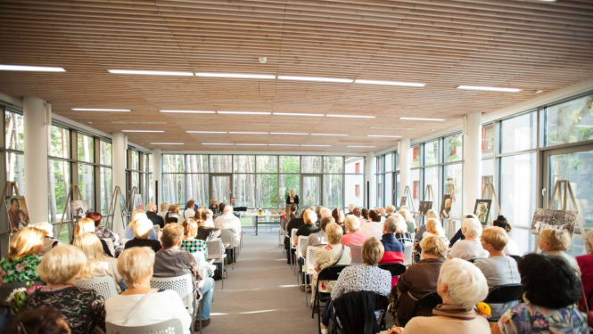 cilvēki klausās lekciju Jūrmalas centrālās bibliotēkas zālē