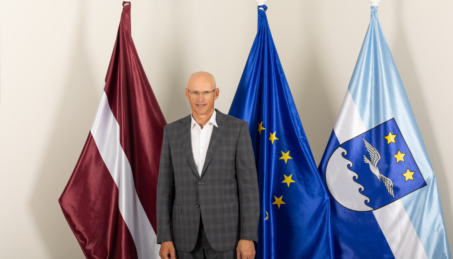 Gatis Truksnis uzvalkā stāv pie Latvijas, Eiropas Savienības un Jūrmalas pilsētas karogiem