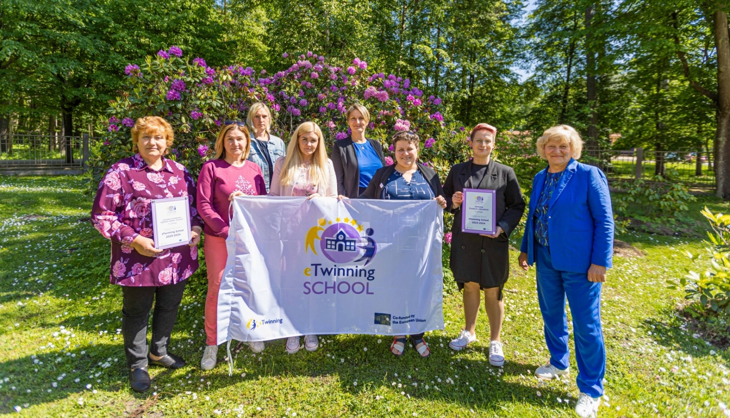 Pedagogi no Jūrmalas Pumpuru vidusskolas un pirmsskolas izglītības iestādes “Zvaniņš”  tur rokā “eTwinning Skola” karogu